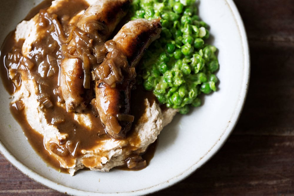 bangers and cauliflower mash with guinness onion gravy and mushy peas