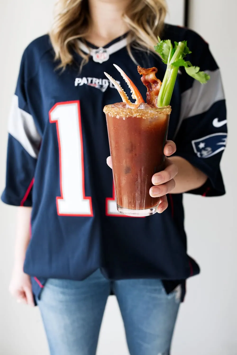 loaded old bay bloody mary with candied bacon and snow crab claw with celery and patriots football jersey