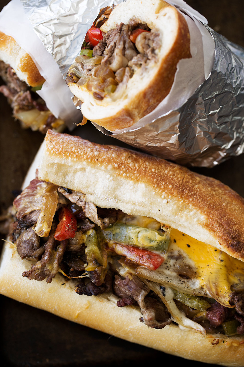 game day closeup philly cheesesteaks made with thinly sliced ribeye cheddar cheese peppers and onions