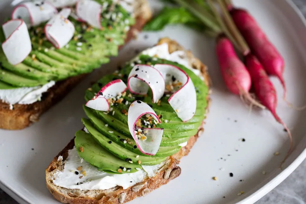 loaded everything bagel spice avocado toast with cream cheese and shaved breakfast radish