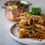 Korean braised pork and kimchi quesadilla stacked on a plate.