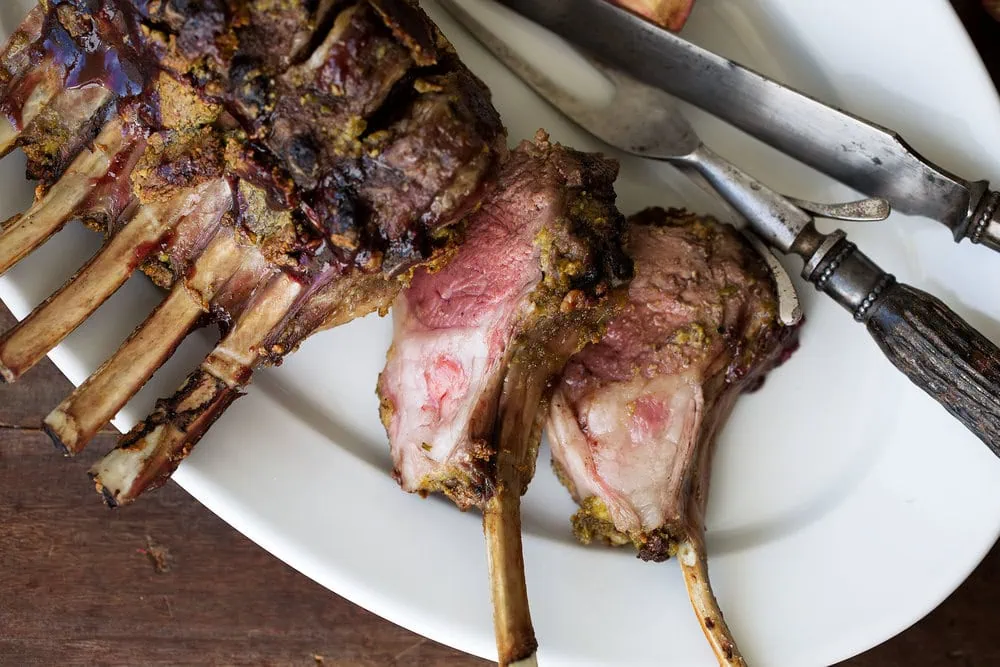 Pistachio Crusted Crown of lamb with Pomegranate Glaze cut into chops cooking with cocktail rings