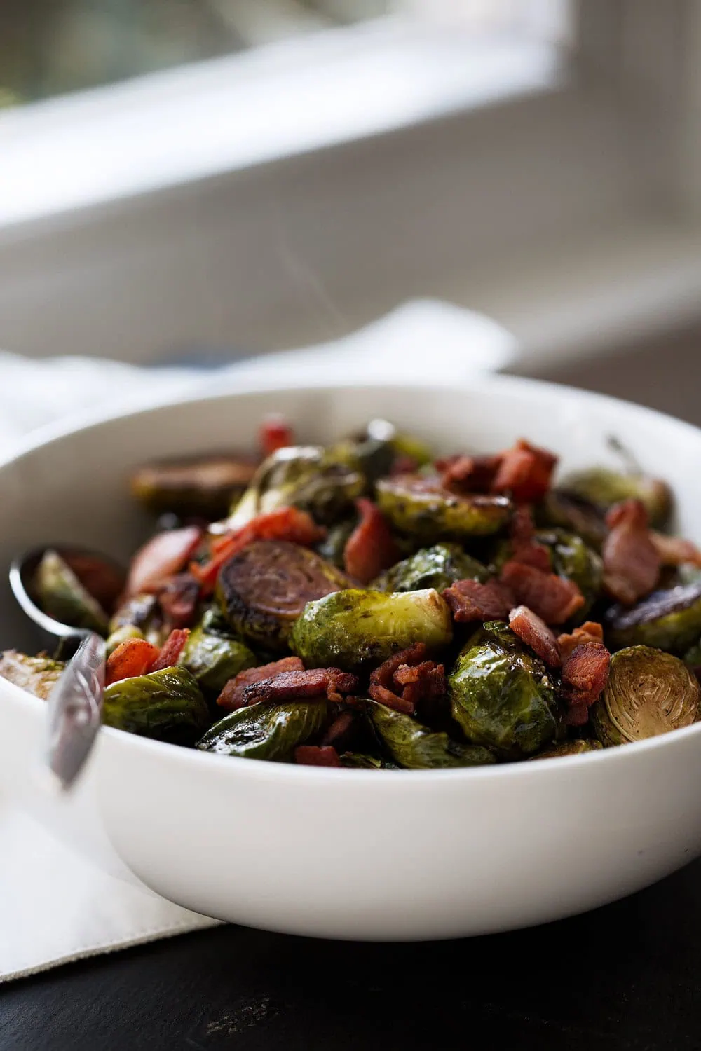 steaming balsamic brussels sprouts with bacon in a white bowl 