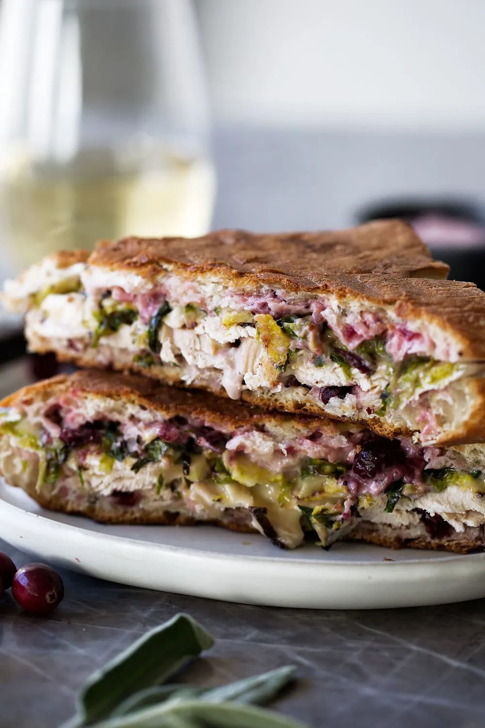 thanksgiving leftover panini with turkey, brie, shredded brussels sprouts and cranberry mayo halved sandwich
