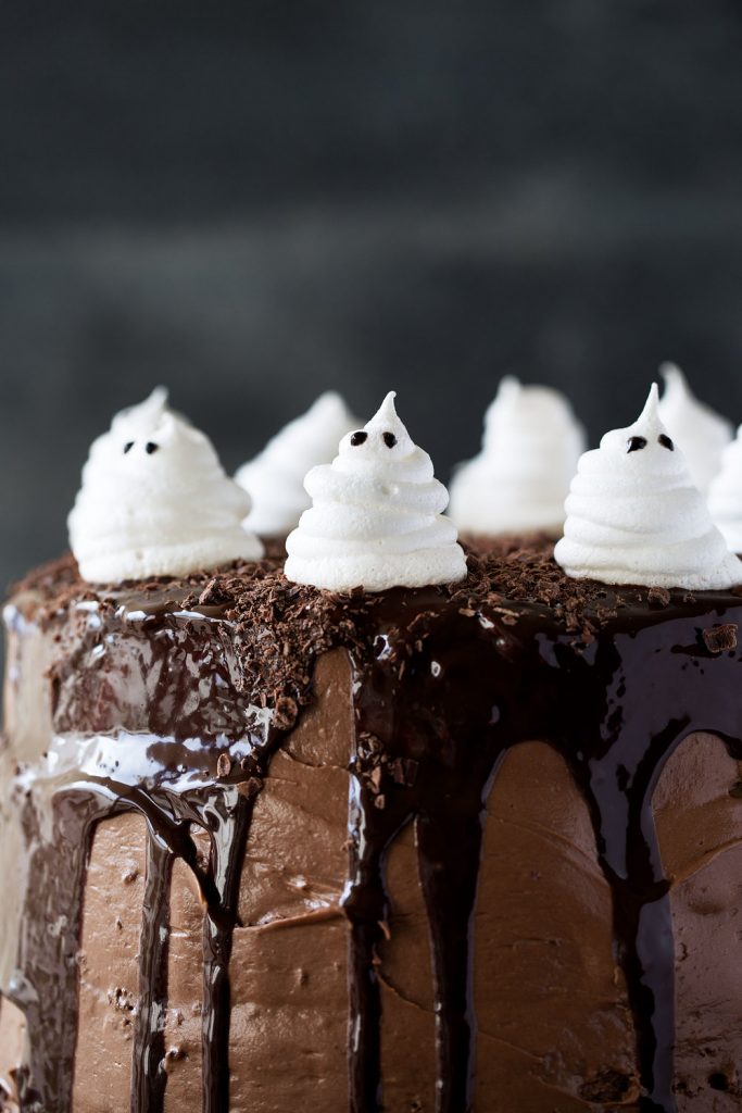 chocolate cake with ganache dripping down sides with meringue ghosts
