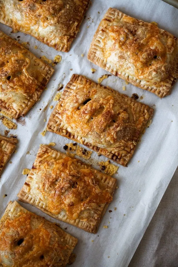 Apple Cheddar Hand Pies on white parchment paper.