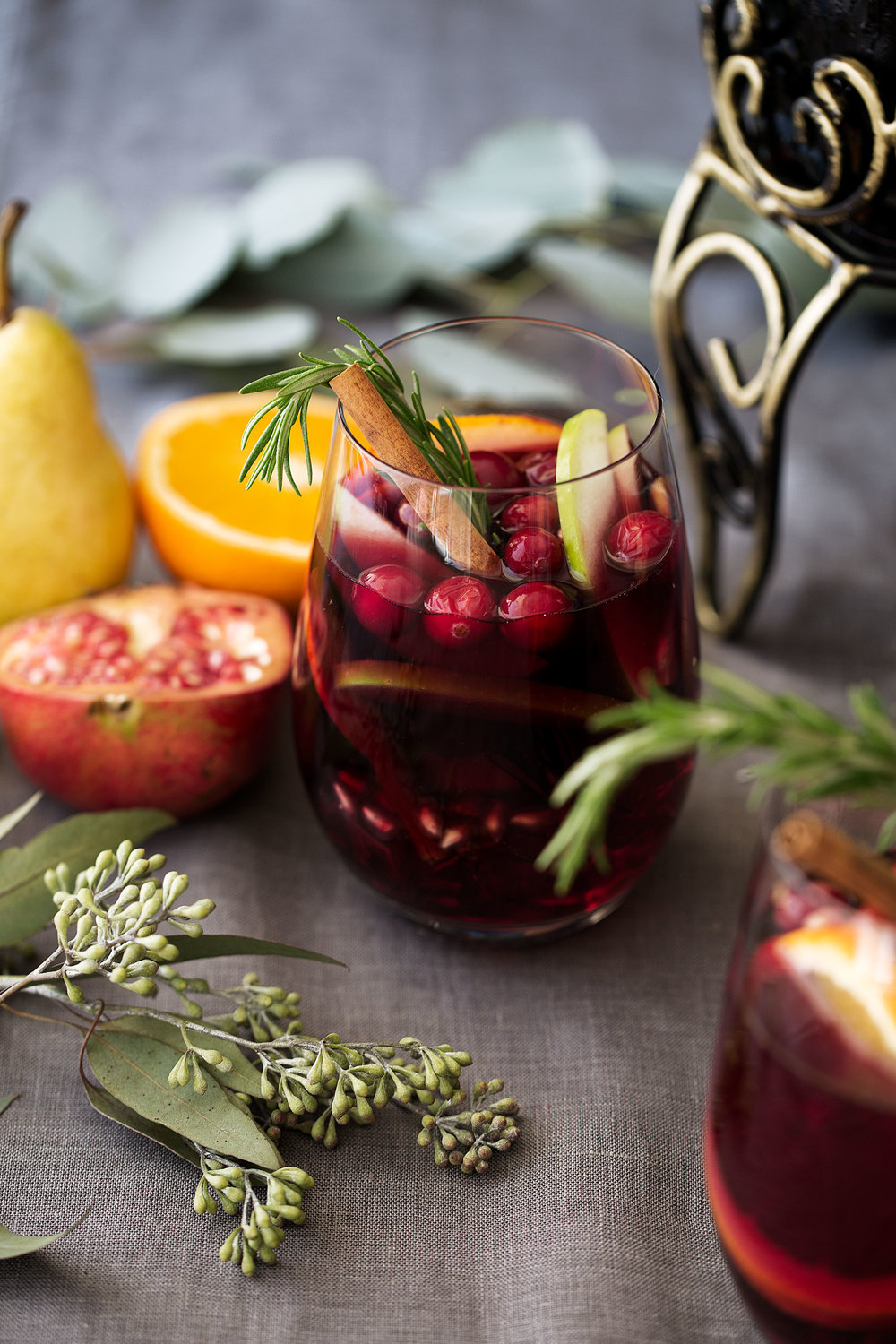 winter red sangria in wine glass garnished with rosemary cinnamon apple slices and cranberries