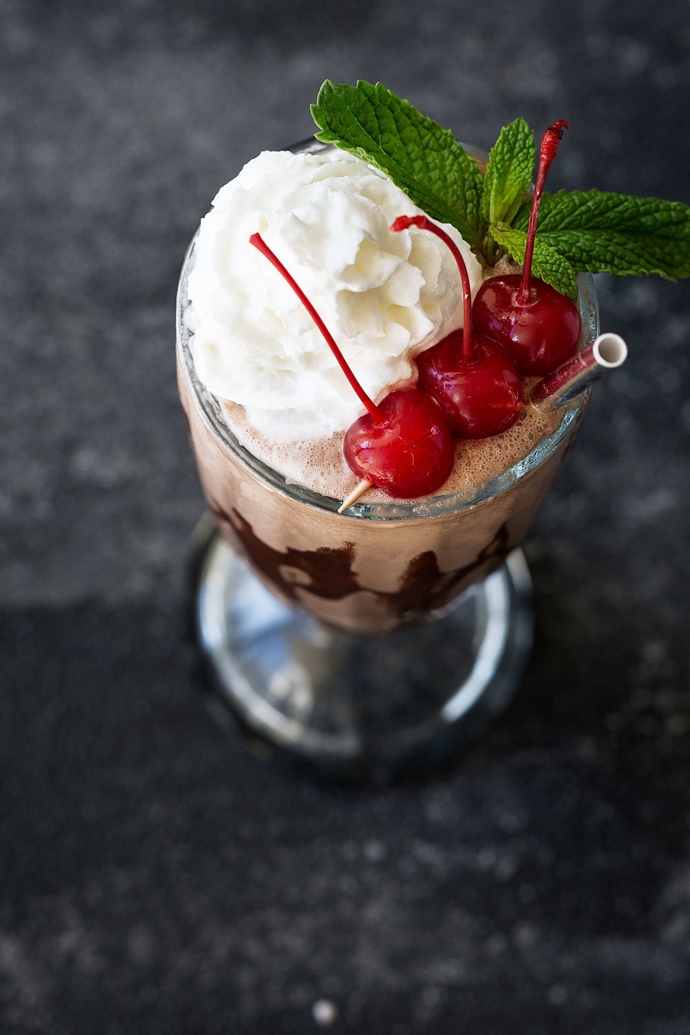 double chocolate malt milkshake with whipped cream cherries and mint garnish