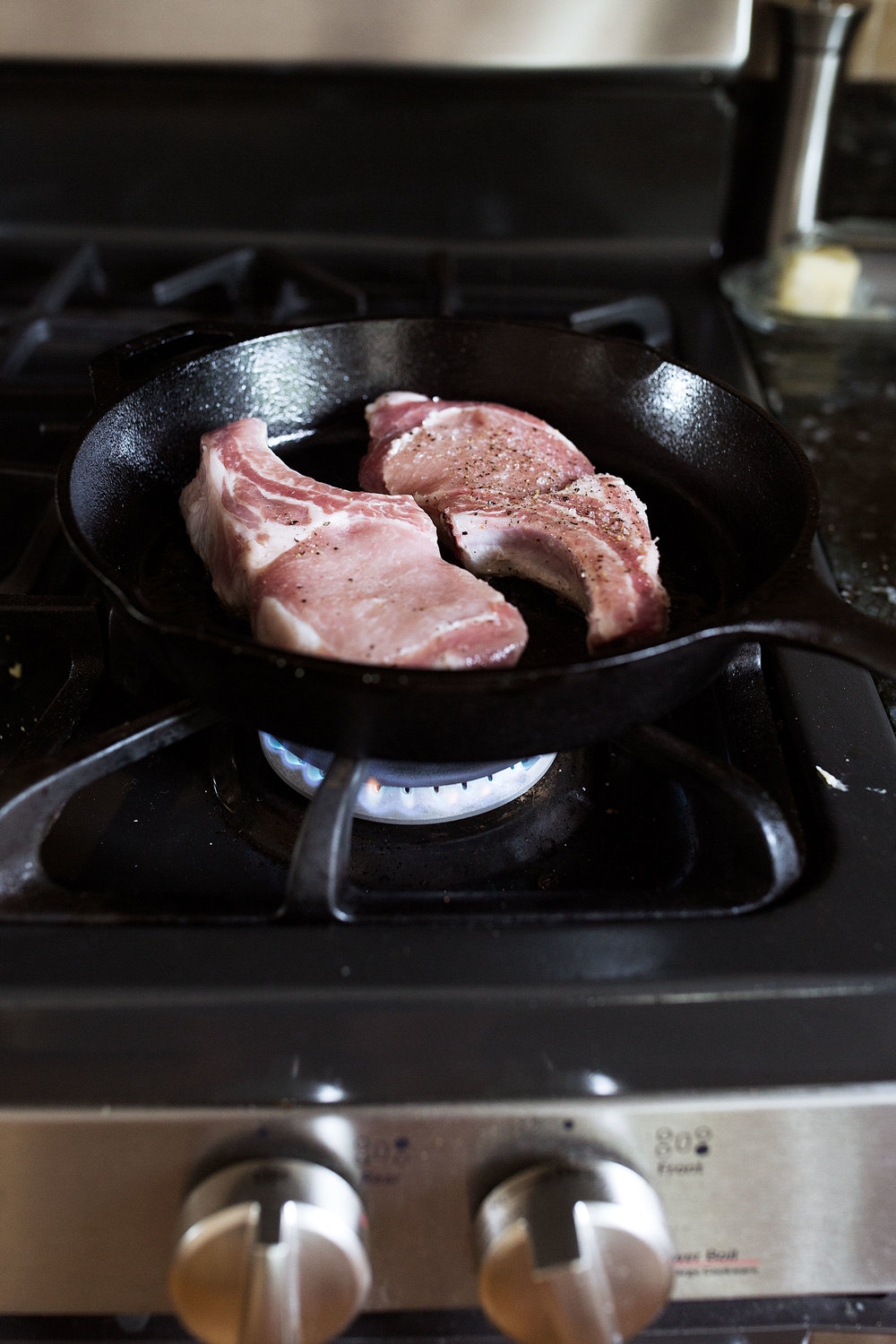 bone-in pork chops seared in cast iron cooking with cocktail rings