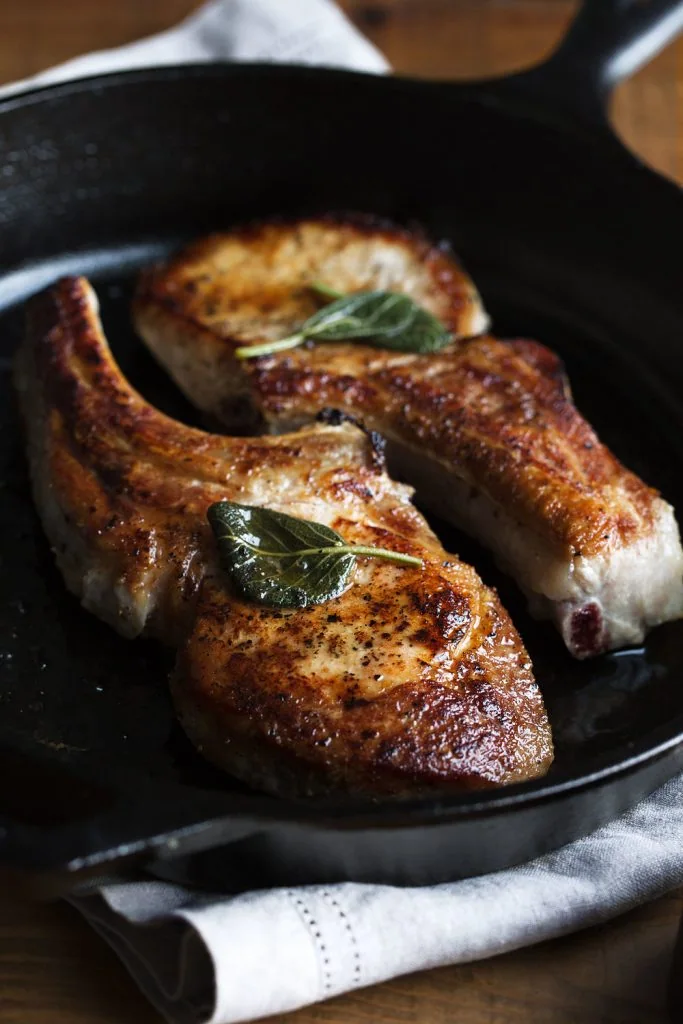 Sage Glazed Bone-In Pork Chops in cast iron pan. 