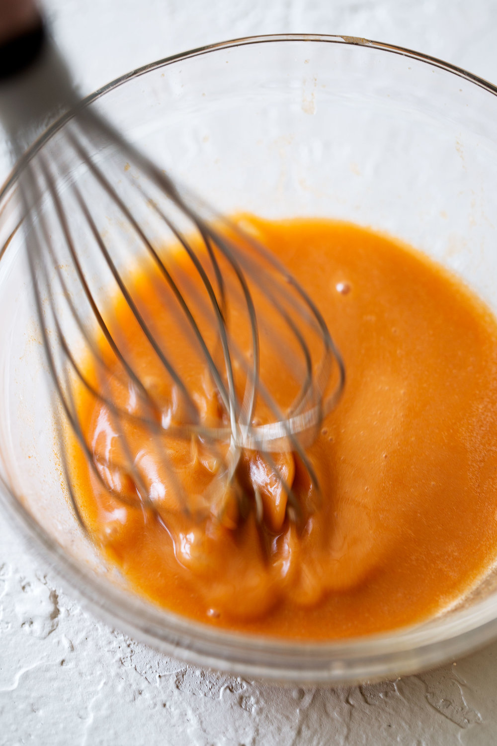 homemade buffalo sauce whisked in bowl
