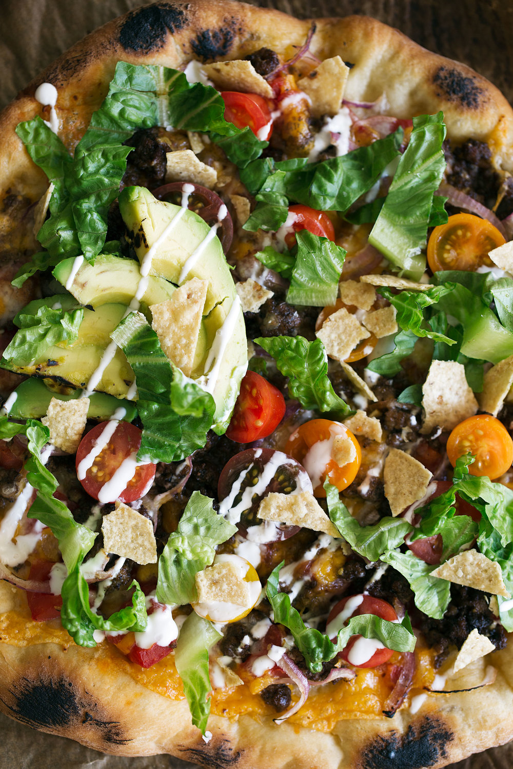 American Taco Pizza with ground beef black beans cherry tomatoes romaine tortilla chips and avocado slices