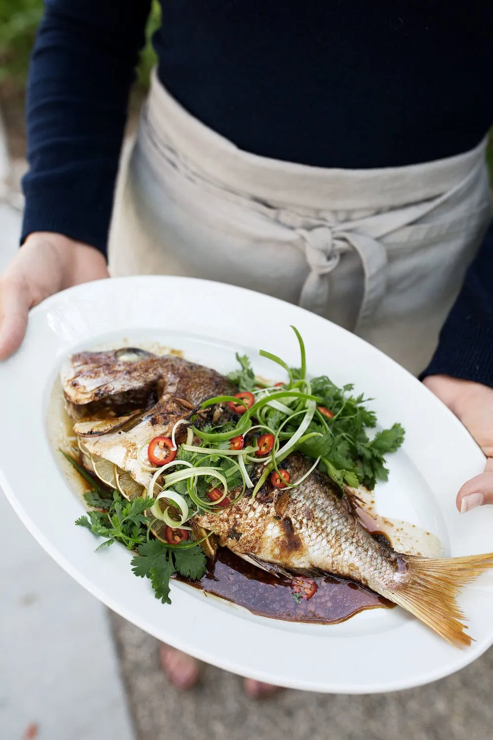 Whole Roast Red Snapper with Asian Spices on platter with cilantro green onion and fresno garnish