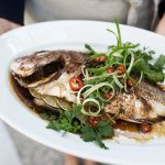 Soy ginger whole roast fish garnished.