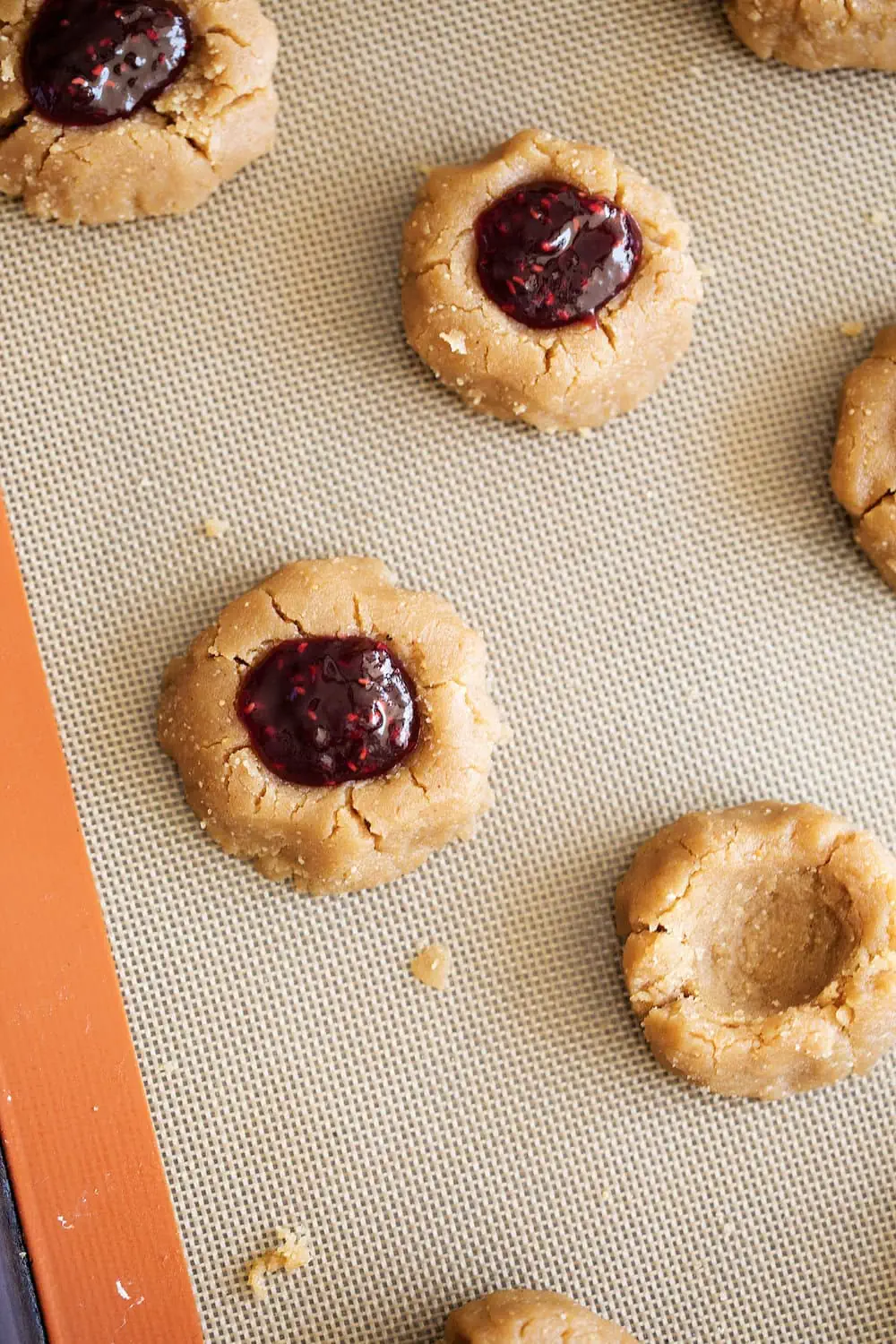 closeup thumbprint pb&j cookies on baking sheet