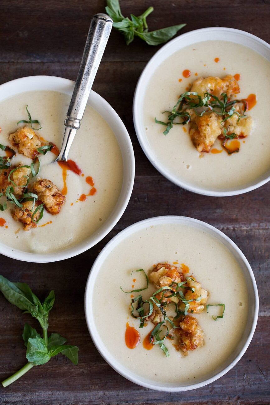 summer corn soup with corn fritters and basil in bowls with spoon.