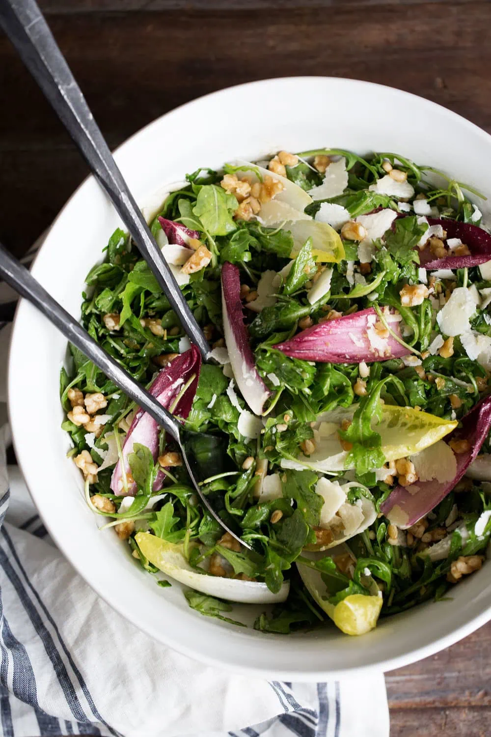 closeup arugula and endive salad with candied pine nuts