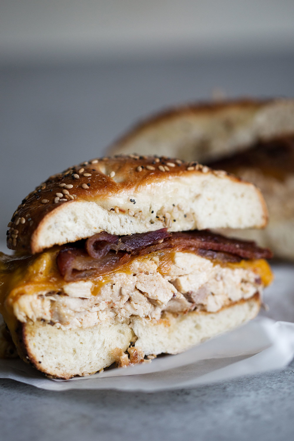 cut chicken salad bagel sandwich with bacon and cheese