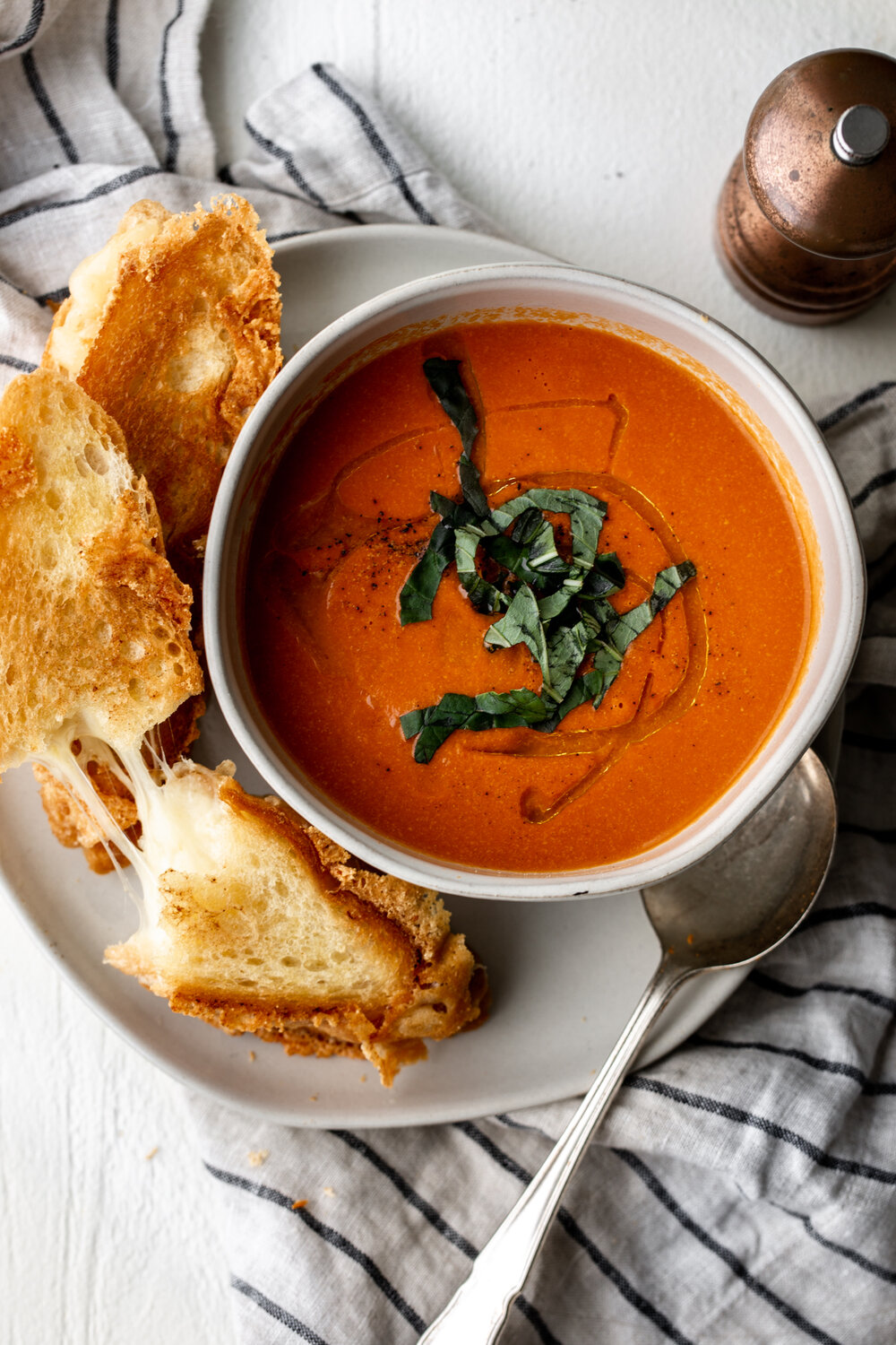 Creamy Tomato Cheddar Soup recipe garnished with basil and grilled cheese