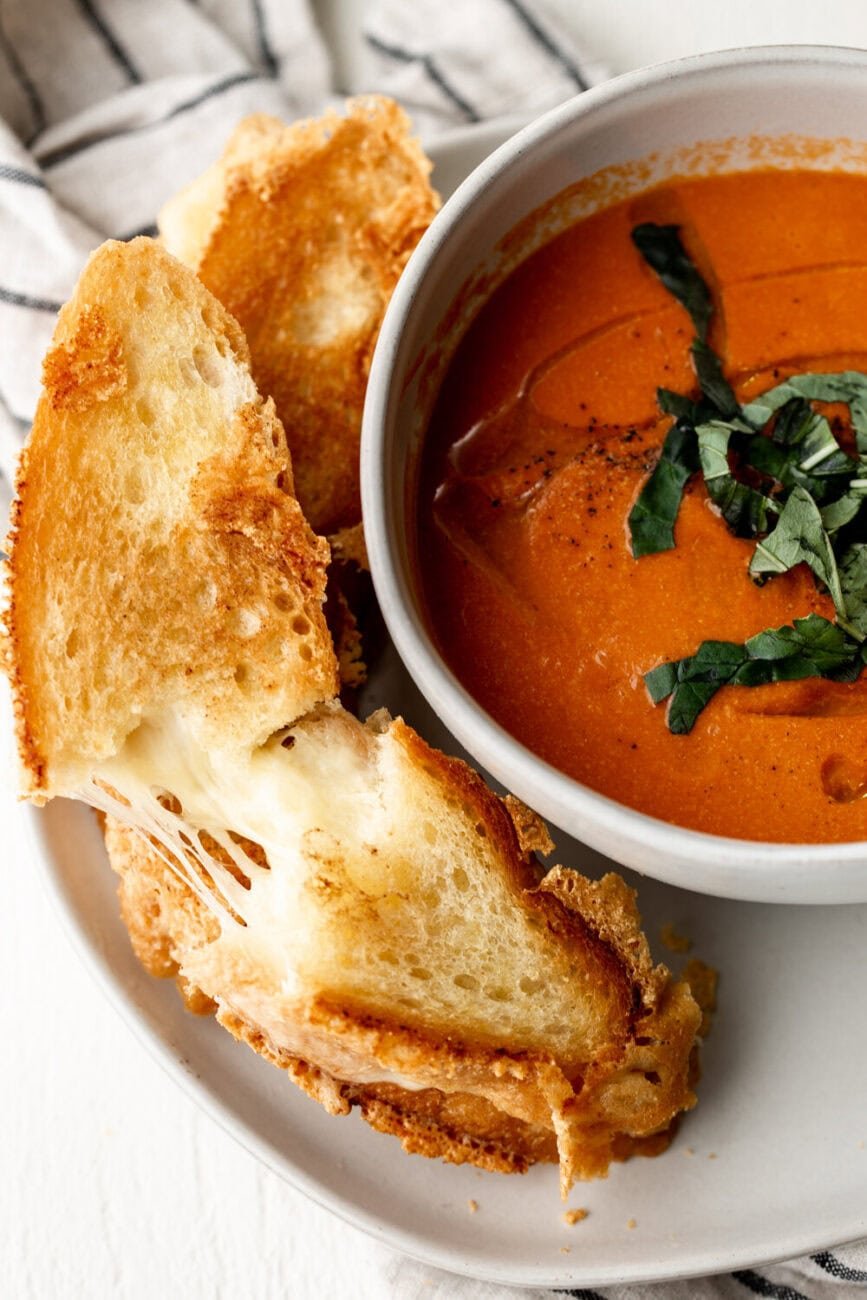 Creamy Tomato Cheddar Soup with grilled cheese pull.