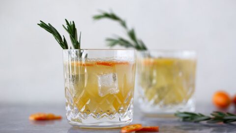 rosemary kumquat gin fizz cocktail recipe in lowball glass with rosemary sprig garnish.