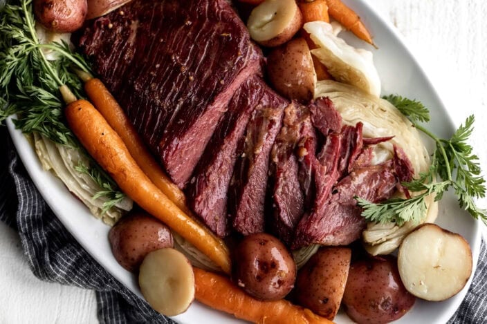 corned beef and cabbage sliced on platter with carrots and potatoes.