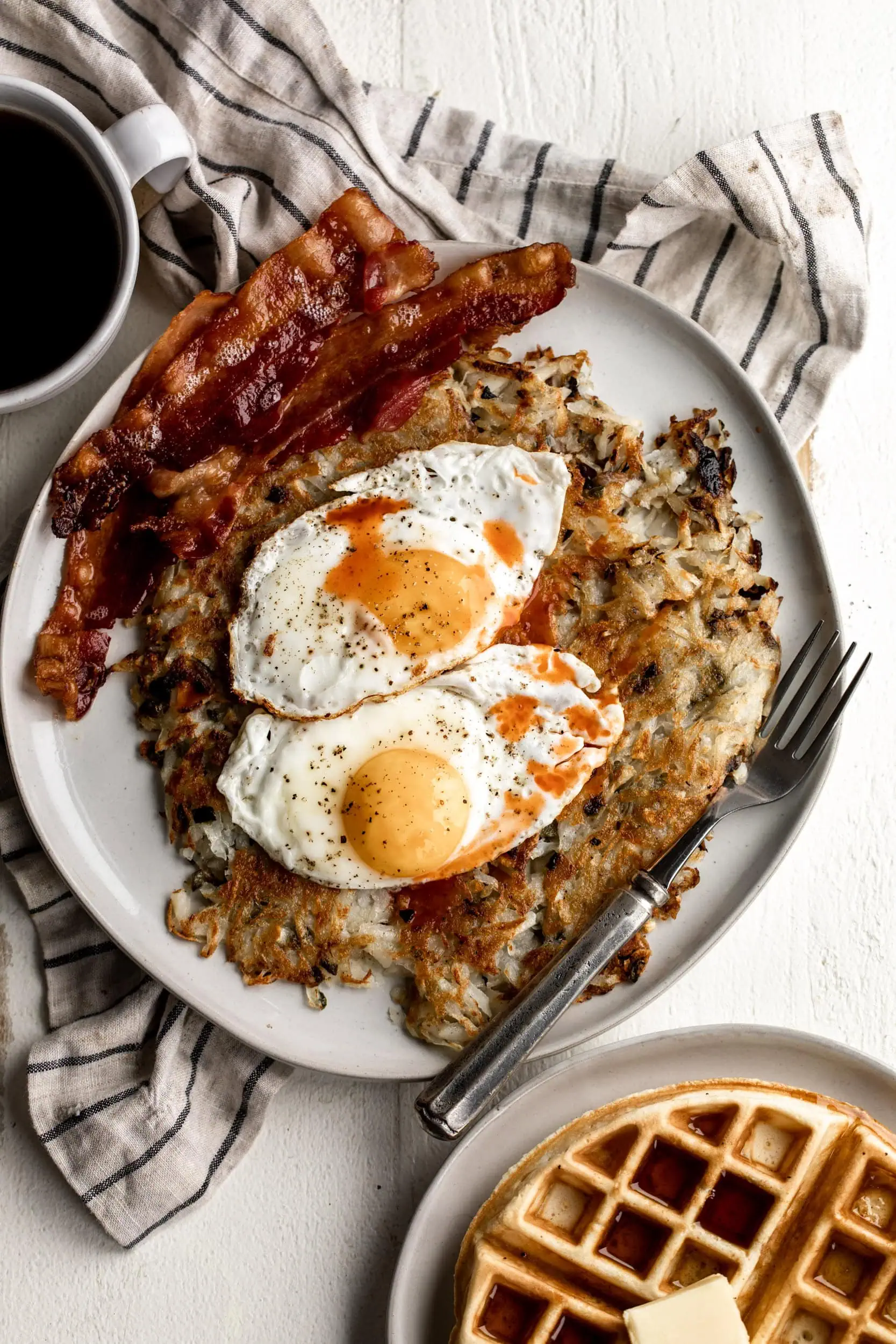 crispy jalapeño hash browns topped with sunny side up eggs and crispy bacon