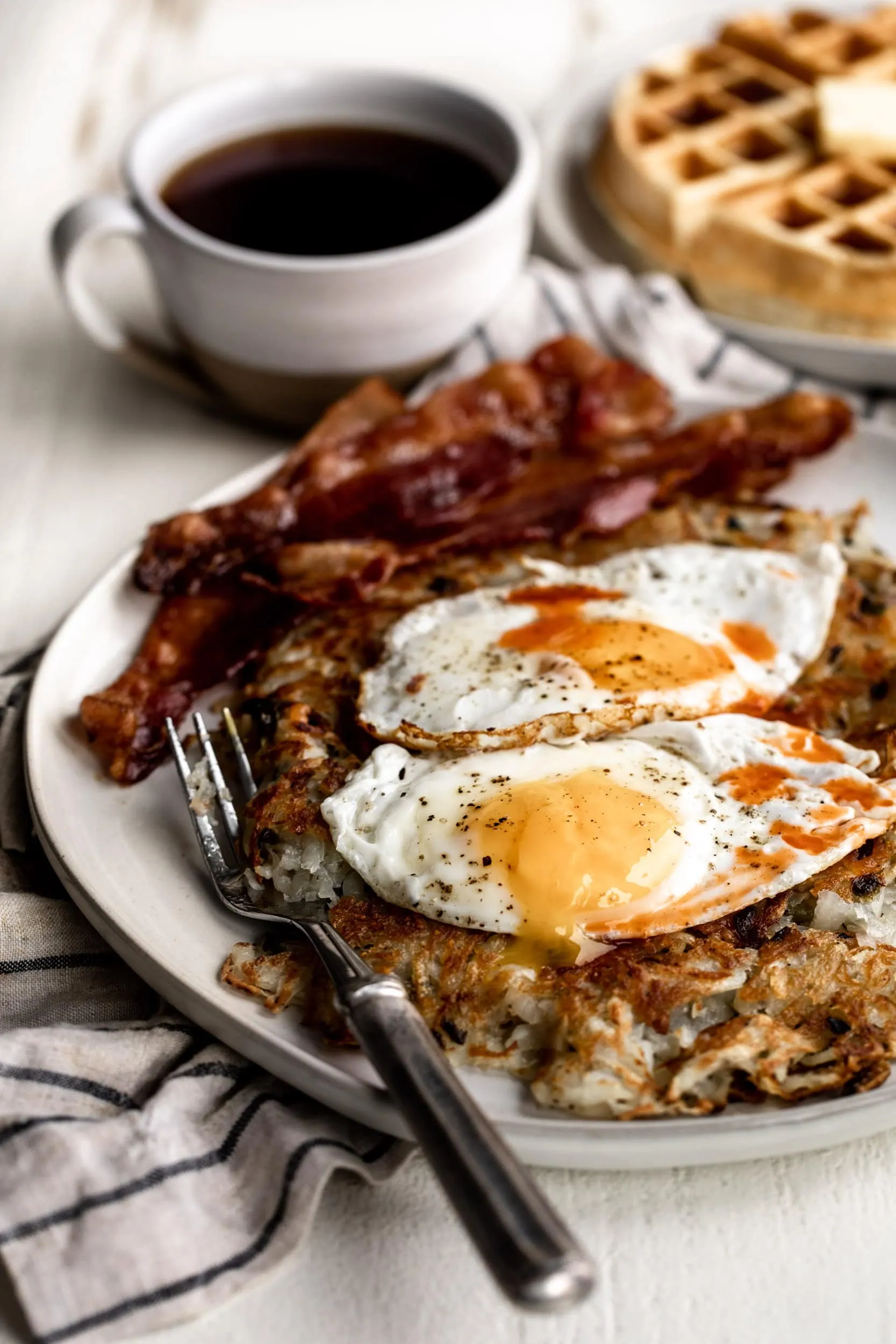 crispy jalapeño hash browns topped with sunny side up eggs and crispy bacon