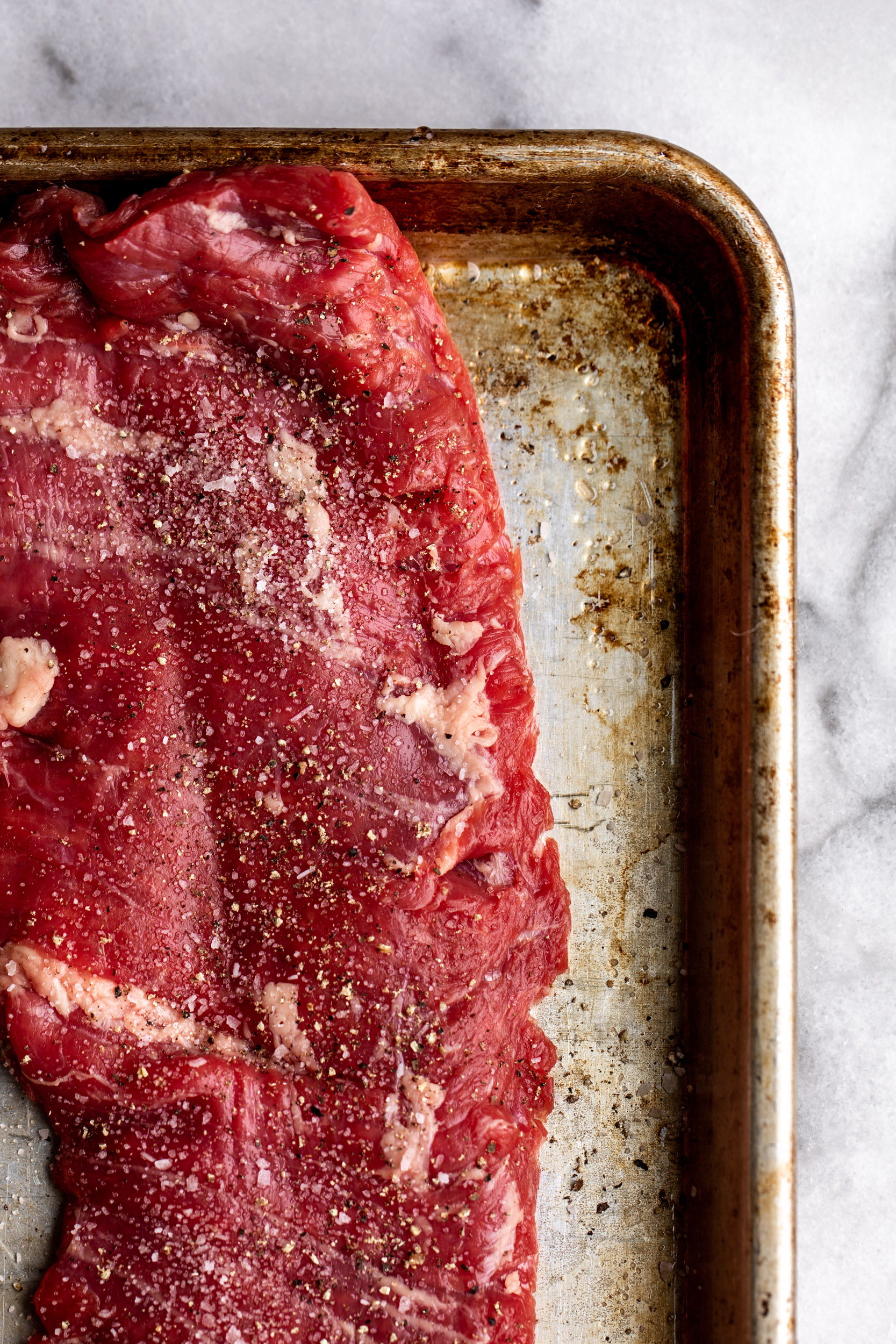 raw steak on a sheet pan