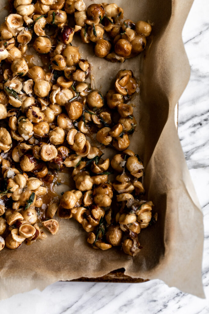 candied hazelnuts spread on a parchment paper baking sheet on marble