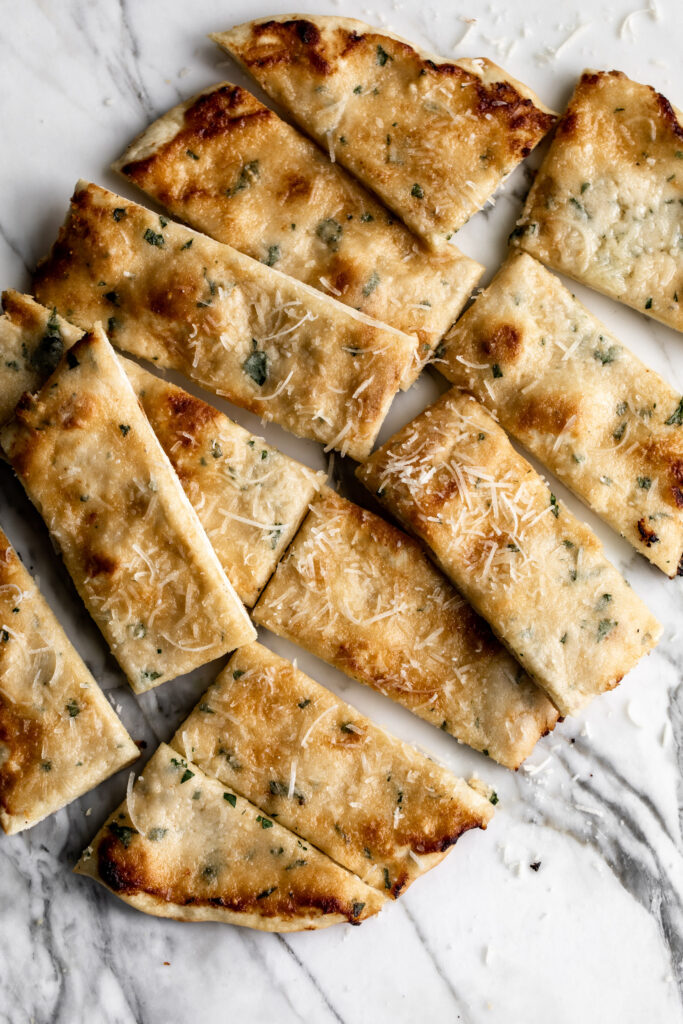 cheesy garlic flatbread cut into slices on marble