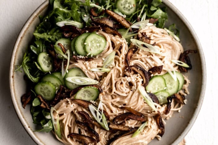 chilled buckwheat soba noodles with crispy shiitake mushrooms, slices of cucumber and green onions.