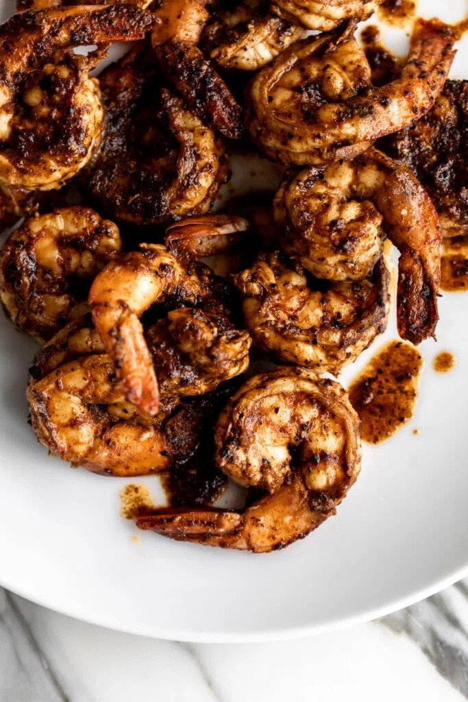 bright red chili powder sautéed tail on shrimp on a white plate