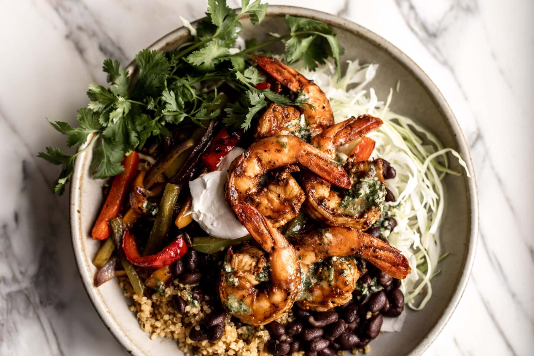 shrimp fajita quinoa bowl over shredded cabbage with black beans.