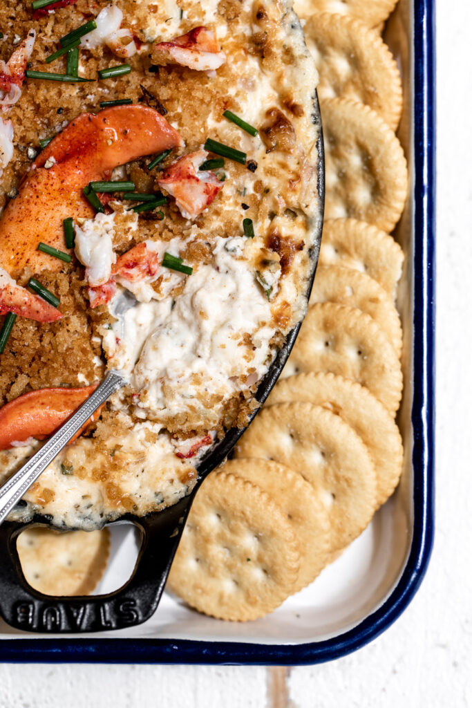 closeup creamy baked lobster dip with breadcrumbs and extra lobster meat on top with ritz crackers