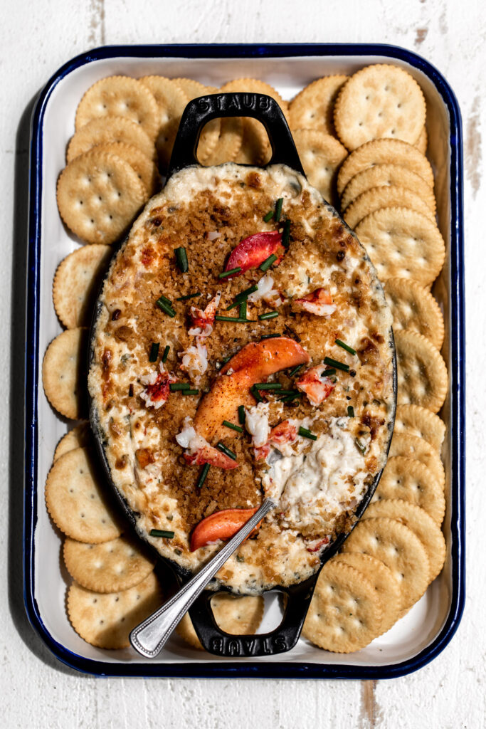 creamy baked lobster dip with breadcrumbs and extra lobster meat on top with ritz crackers