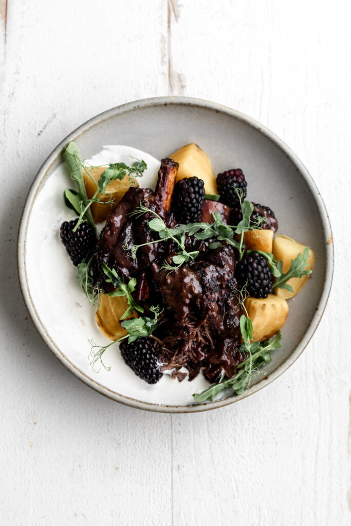 braised ribs with whipped ricotta on the side of the bowl with yellow beets and arugula | How to Style Food Photos