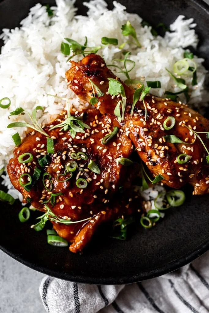 Braised Garlic Gochujang Chicken Legs over white rice with sesame seeds.