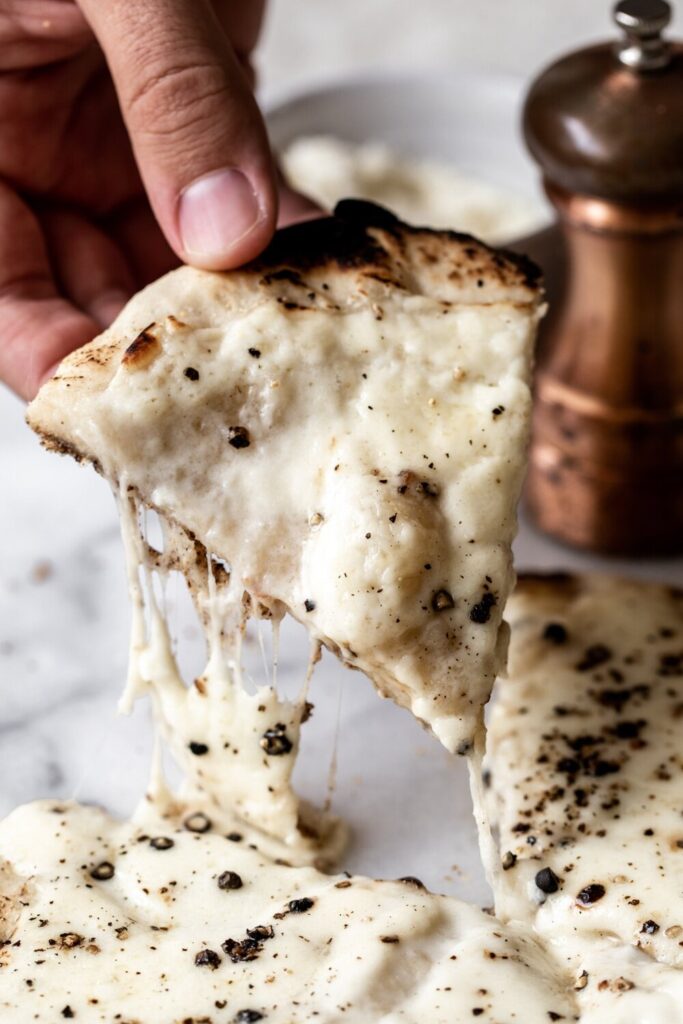 hand holding slice of cacio e pepe pizza | How to Style Food Photos