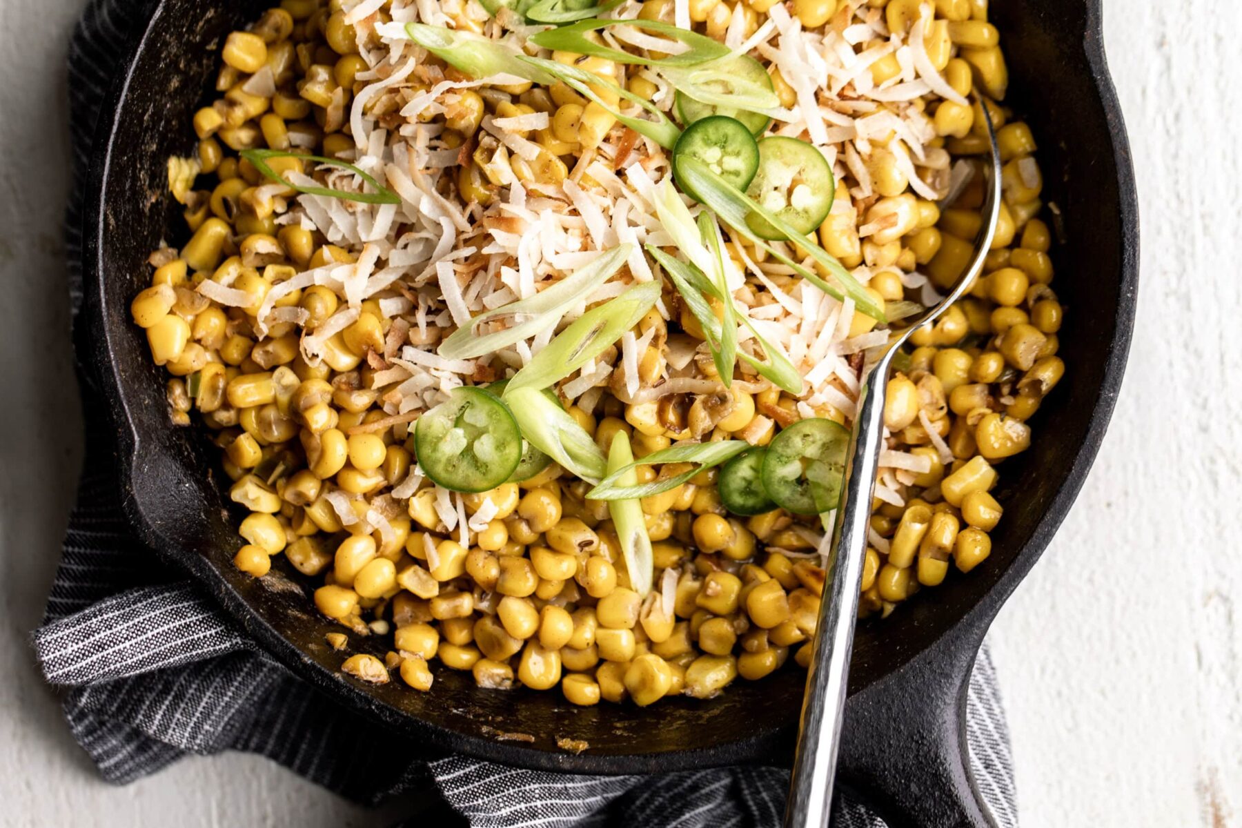 creamed corn made with coconut milk and Jamaican spices in a black cast iron pan.