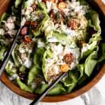 crab salad with avocado, cherry tomato, and puffed quinoa over butter lettuce in a wood bowl