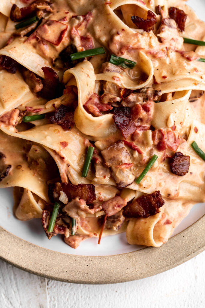 closeup easy creamy tomato and bacon pasta on a ceramic plate