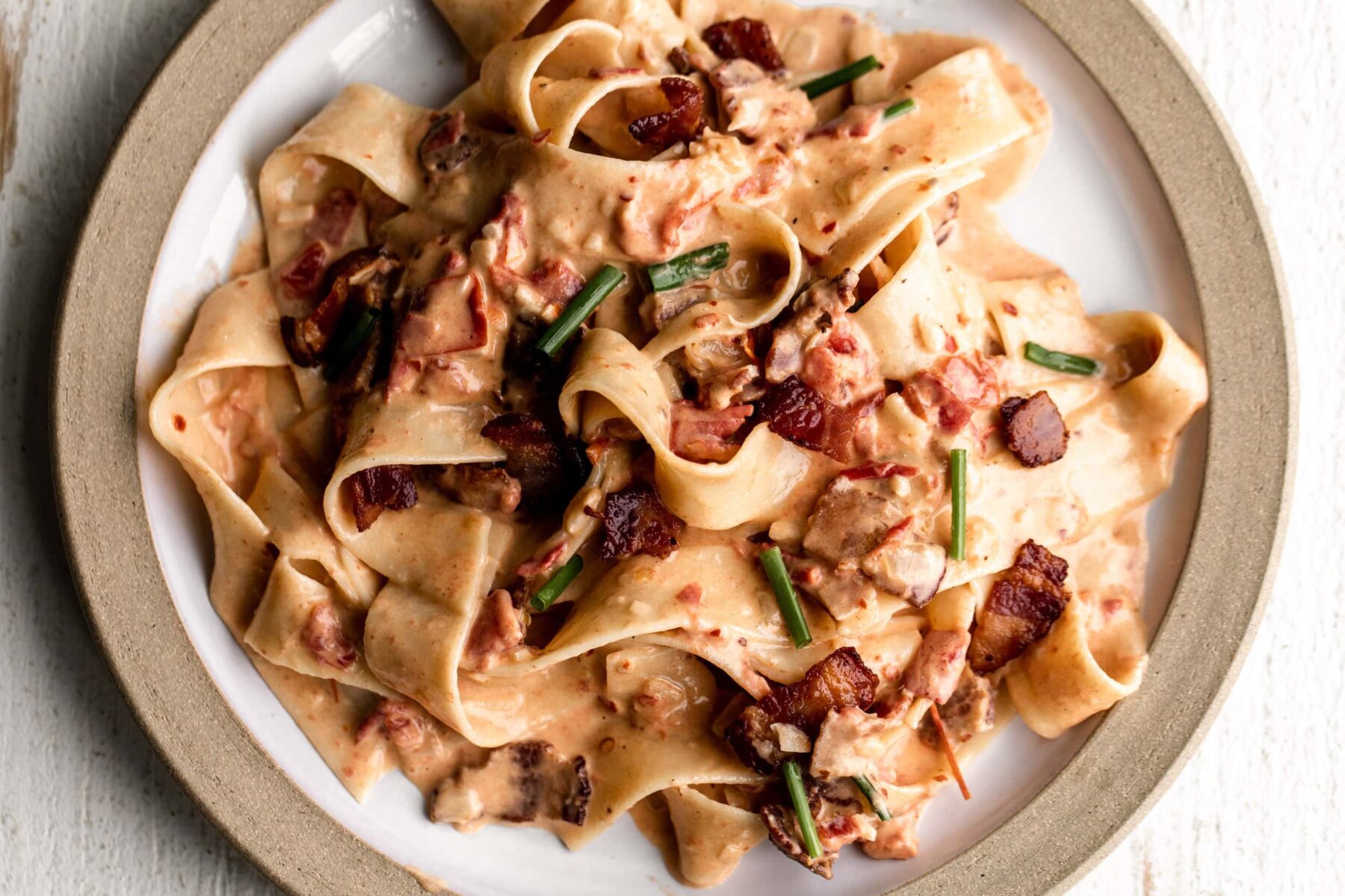 easy tomato and bacon pasta recipe on ceramic plate.