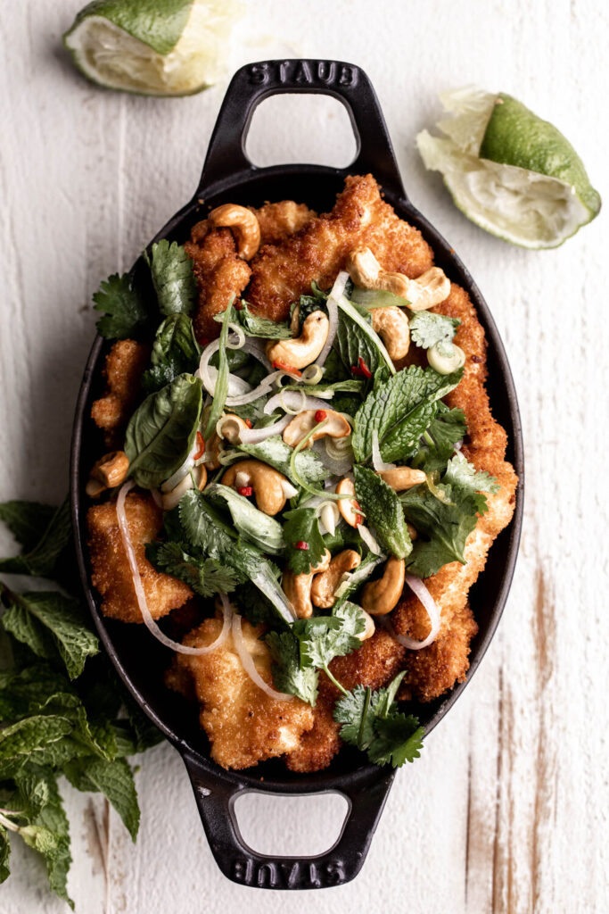 fried fish with herbs in a black serving dish | How to Style Food Photos