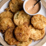 In fried green tomatoes Slices of green tomato are tossed in buttermilk and fried in a flour and cornmeal batter to crunchy golden-brown perfection and then paired with Mississippi comeback sauce