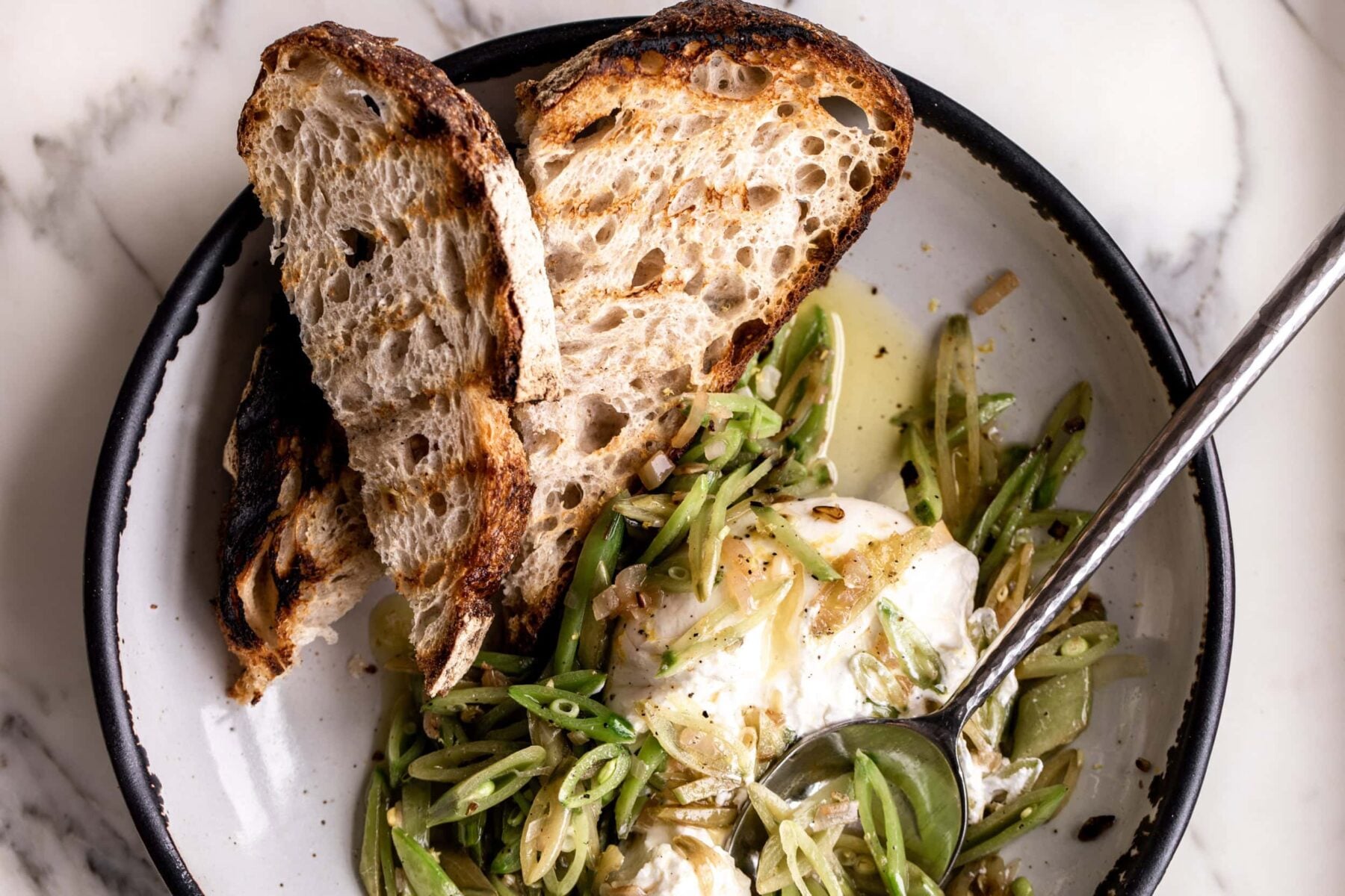 sugar snap peas are thinly sliced on the bias with shallots served over creamy burrata with grilled bread.