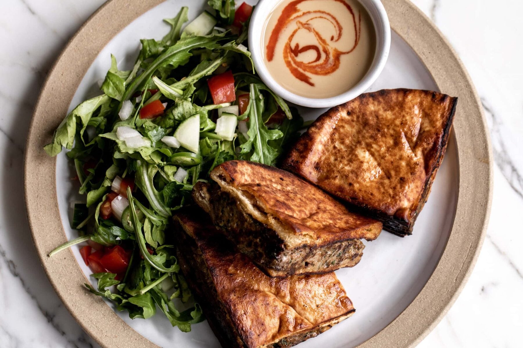 Arayes are meat-stuffed pitas, served filled with kofta and a side green salad and tahini.