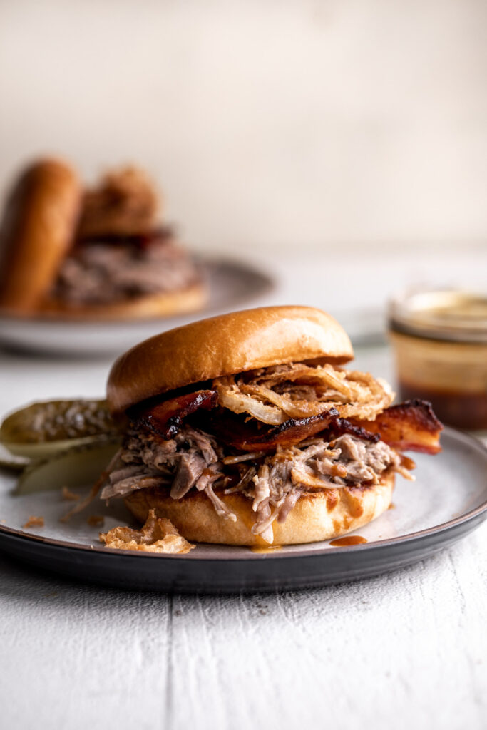 classic pulled pork sandwich made with braised pork bacon, onion rings and cheddar cheese on a brioche bun