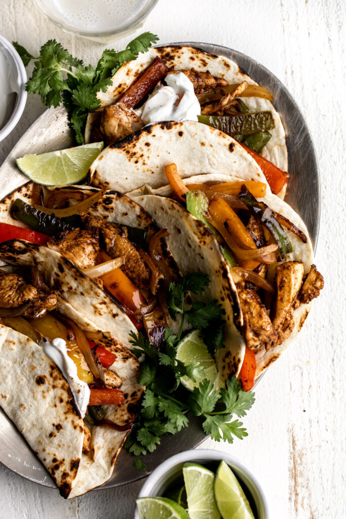 Strips of chicken breasts are marinated in tequila, lime and spices then sautéed and served with onions and peppers on flour tortillas.