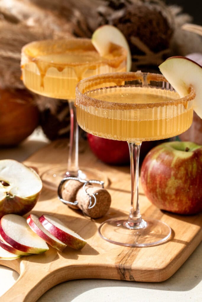 apple cider mimosa cocktail in coupe classes with a cinnamon sugar rim.